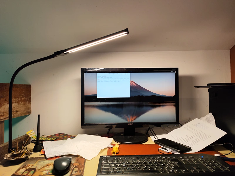  A computer screen on a desk, under a lamp, an eaten apple is decaying and burned incense sticks add to the mystical feeling of the scene.